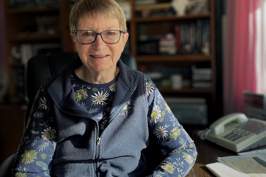 Mary smiles sitting at her desk.