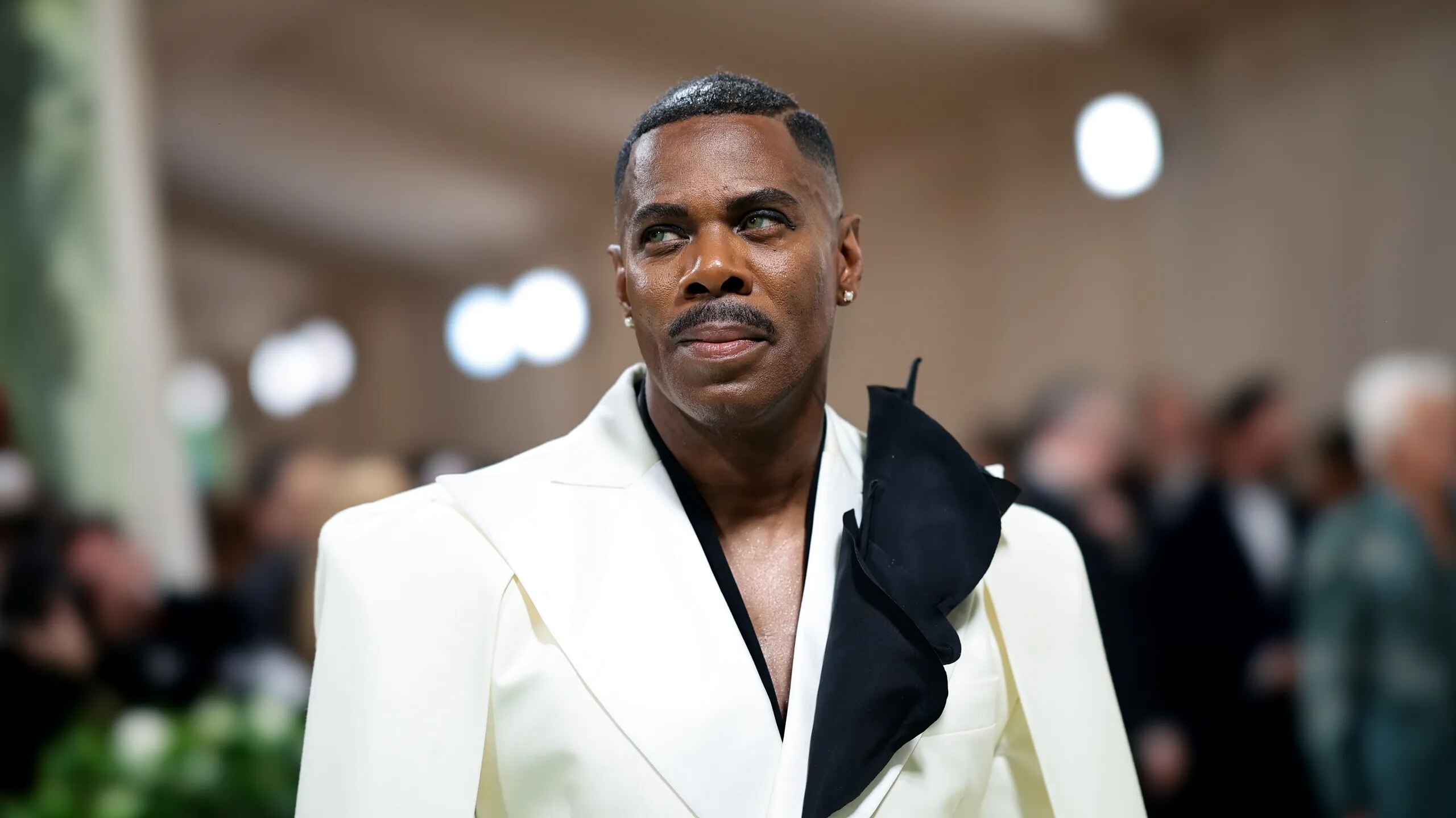 Mid shot of Colman Domingo wearing a white suit with black flourish on his lapel
