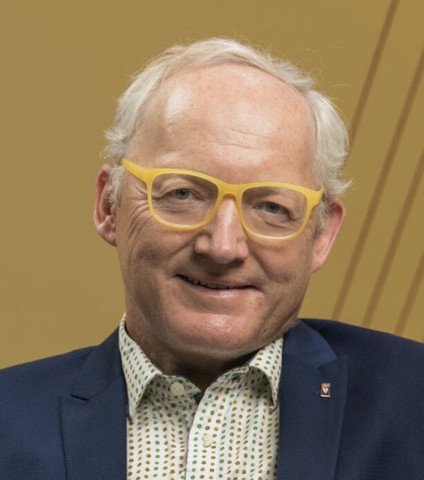 A white man with short grey hair and yellow glasses