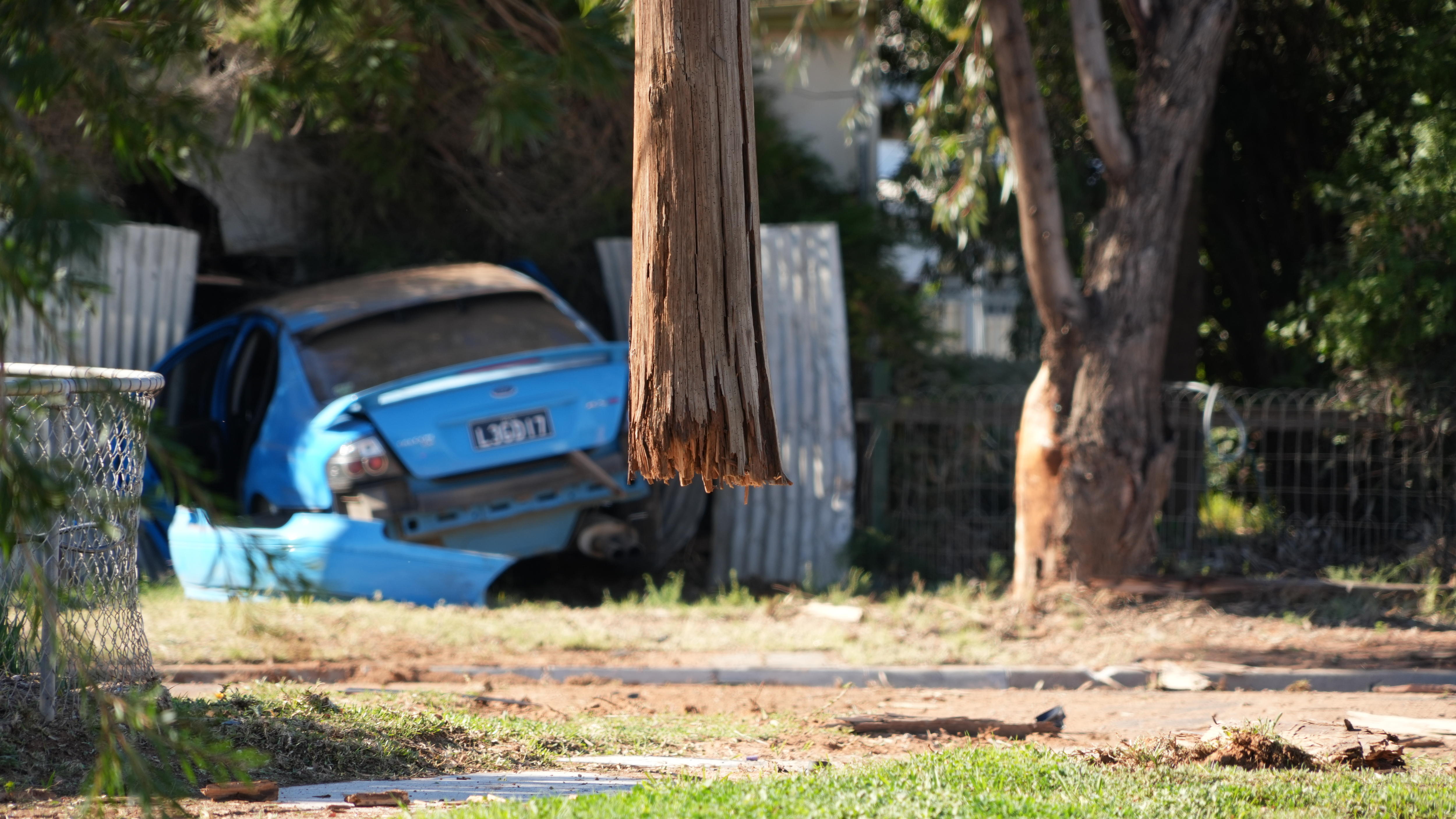 The remains of a wooden power pole, suspended in the air after a car crashed through it