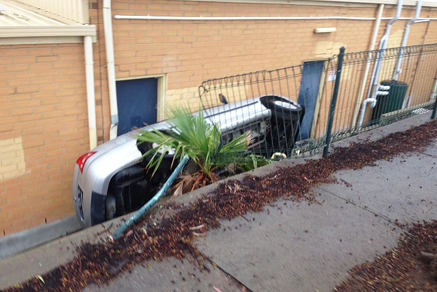Car wedged between a wall and a shop