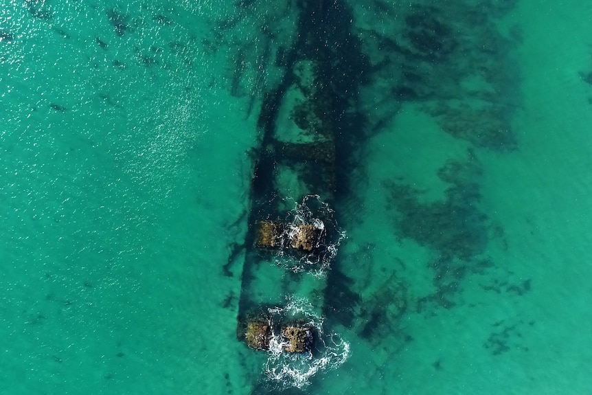 An aerial view of clear water and a shipwreck