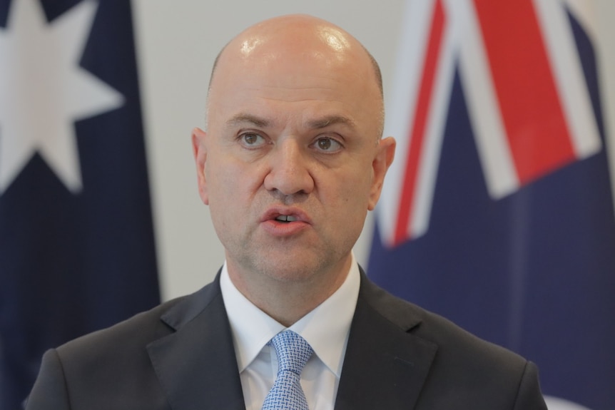 Head shot of Chief Health Officer John Gerrard with Australian flag in background.