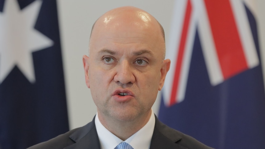 Head shot of Chief Health Officer John Gerrard with Australian flag in background.