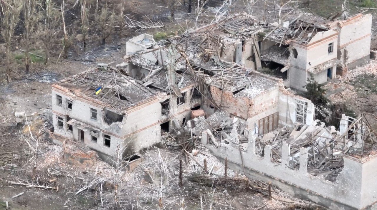 Ukraine's flag atop a large destroyed building, seen from above