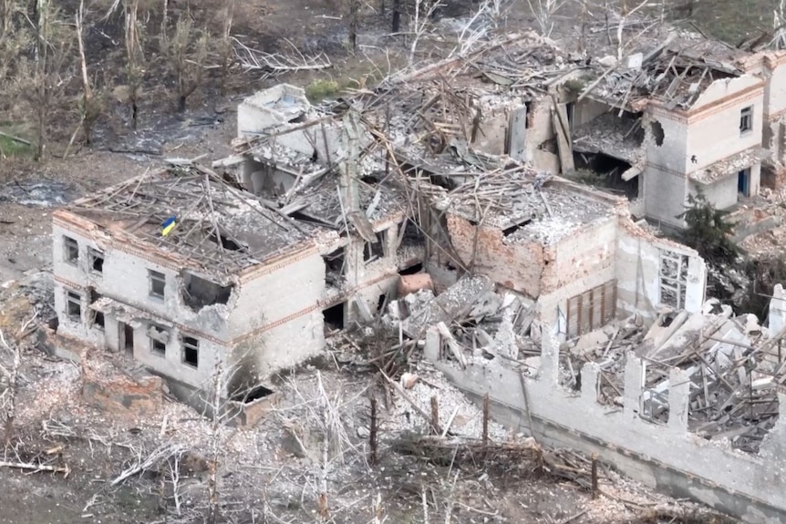 Ukraine's flag atop a large destroyed building, seen from above