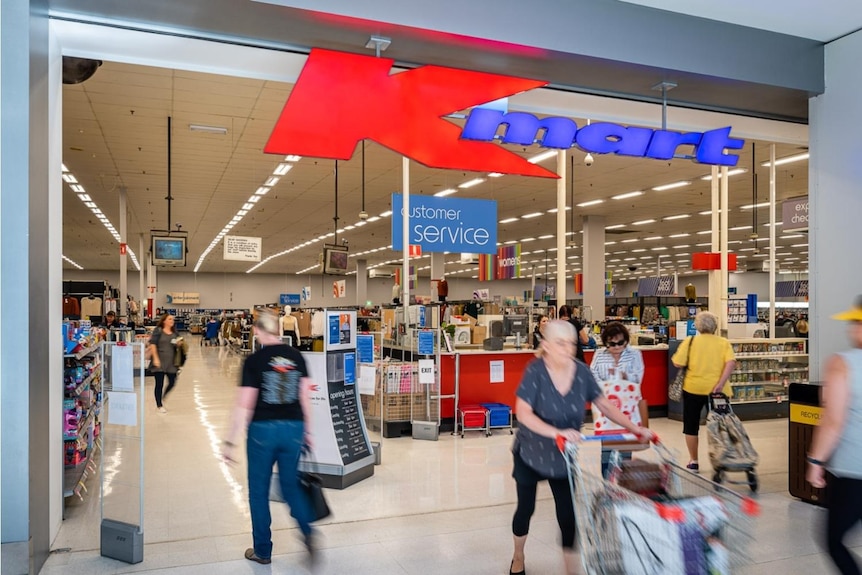 entrance to shopping stor with Kmart signage and customers walking and with trolleys by customer service desk