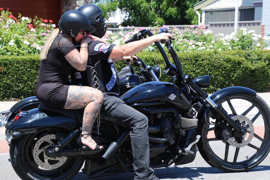 A heavily tattooed woman sits on the back of a bike at Rebels bikie boss Nick Martin's funeral.