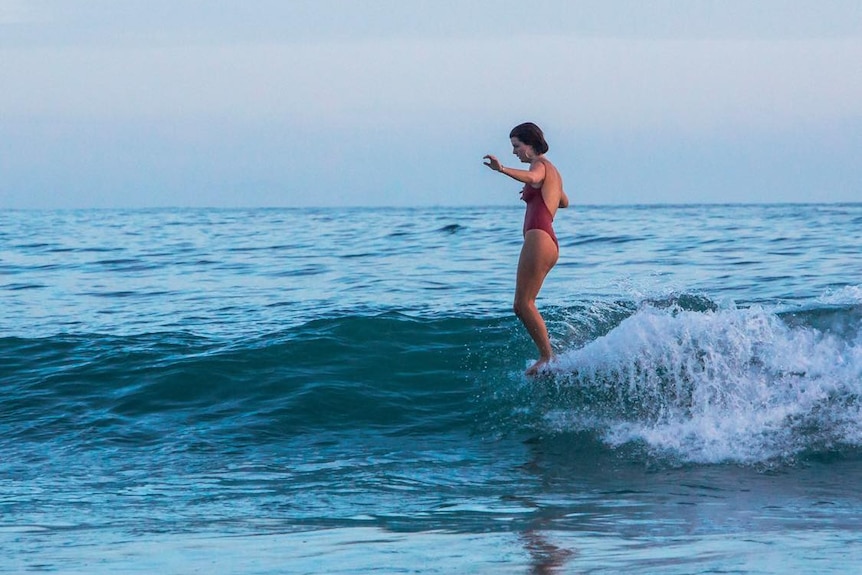 Female standing up on her surf board on the water 