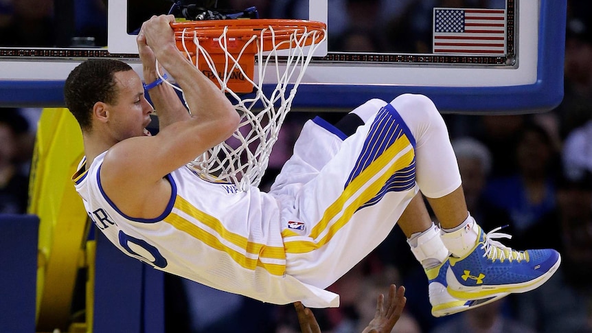 Stephen Curry hangs on the basket