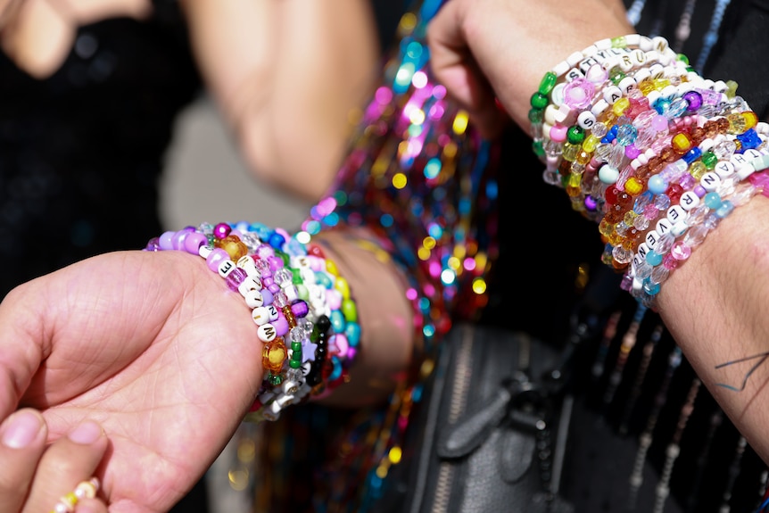 a close up shot of two wrists covered in friendship bracelets