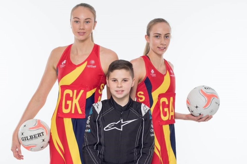 Two girls wearing netball dresses with young boy in a racing suit.