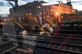 Women on their mobile phones are reflected in a train window.