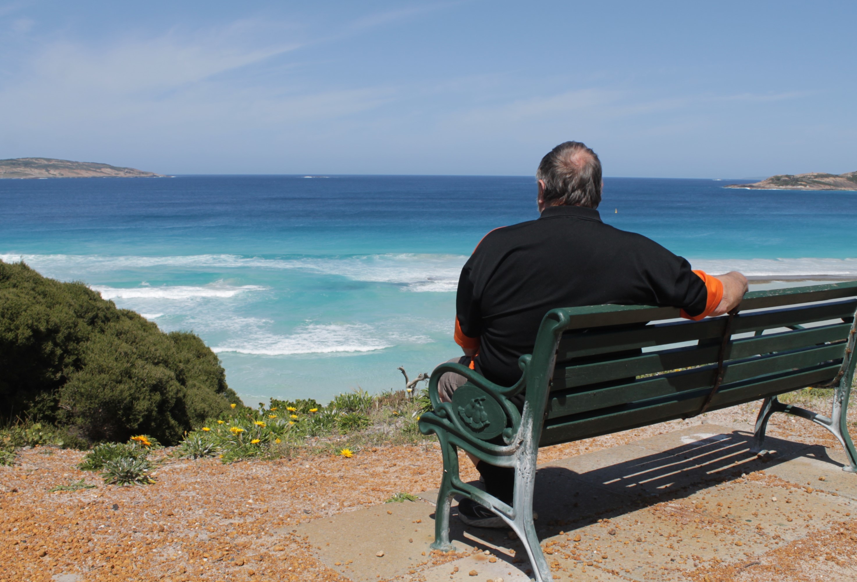 Greg sits on a bench overlooking the tranquil ocean