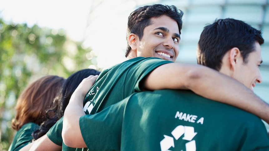 Four people wearing green T-shirts that say "make a difference".