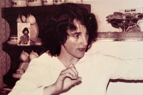 Young woman with dark hair makes expressive gesture in a black-and-white picture.