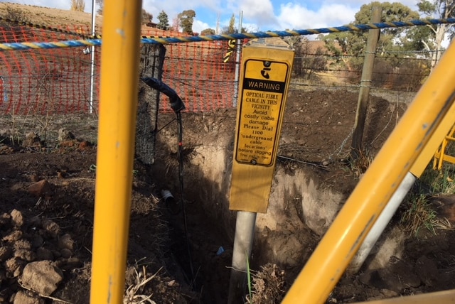 A large hole in the ground surrounded by metal barricades.