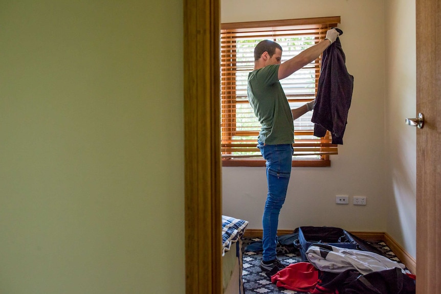 Ben Morley holds up and inspects a jacket.