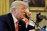 Donald Trump on the phone as he sits at his Oval Office desk