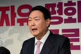 South Korean man in a suit speaking at a conference.