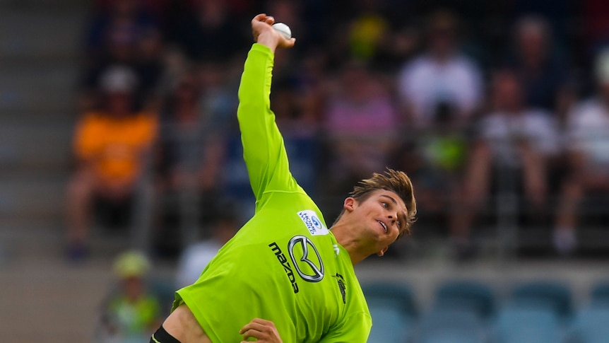 Chris Green bowls a ball wearing a florescent yellow green cricket kit