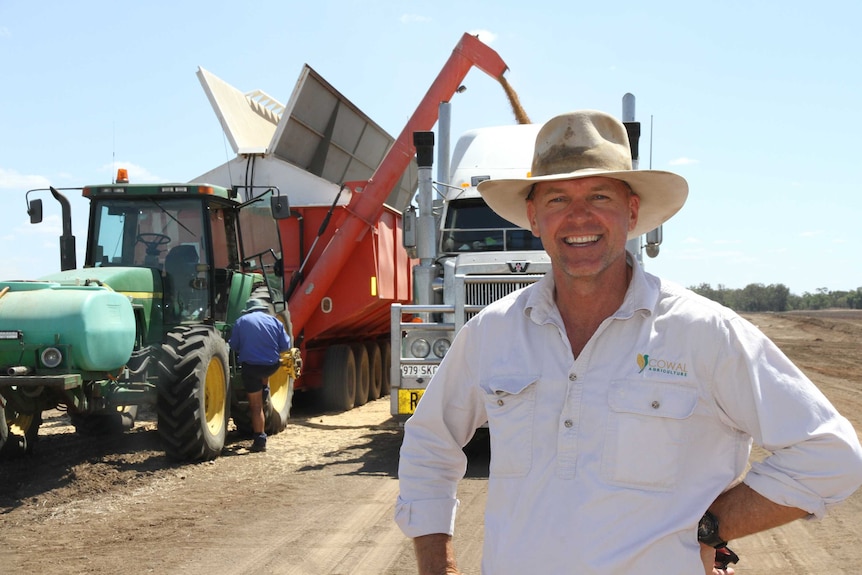 Farmer Hamish Millar stands in front of a grain truck as the harvester unloads the chickpeas