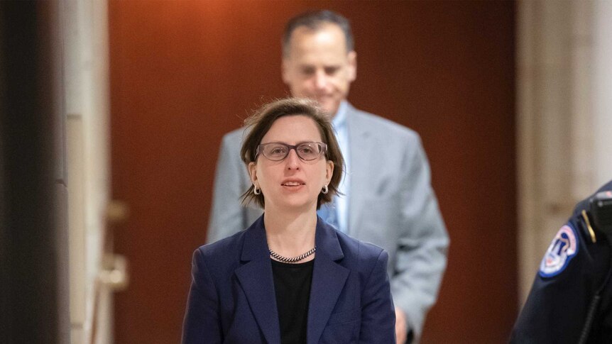 Laura Cooper walks along a corridor towards the camera