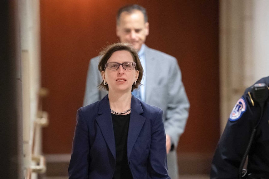 Laura Cooper walks along a corridor towards the camera