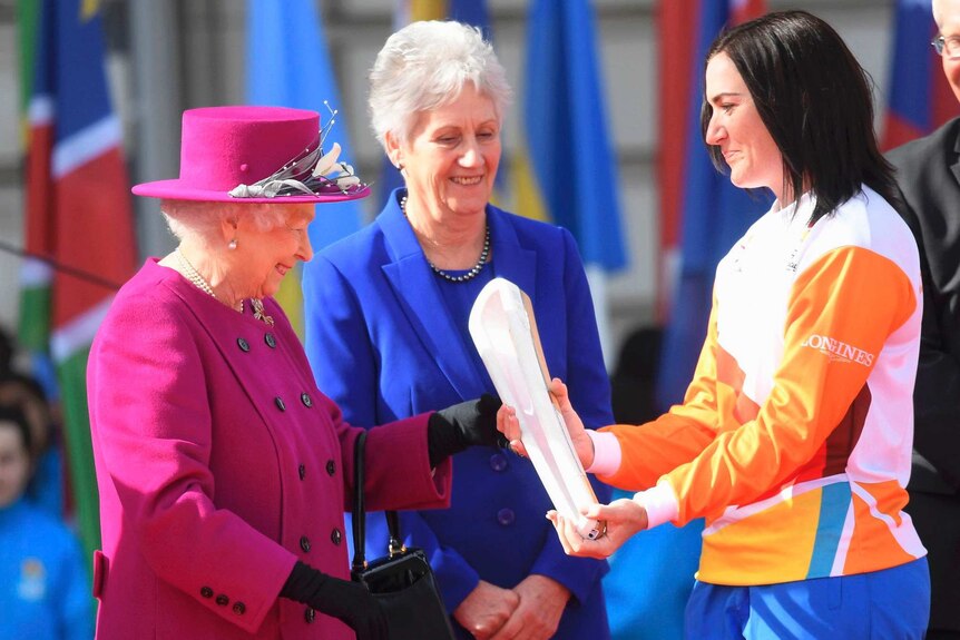 Anna Meares receives the Commonwealth Games relay baton from the Queen