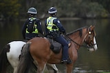 WA Police officers on horseback look out over the Swan River in Maylands.