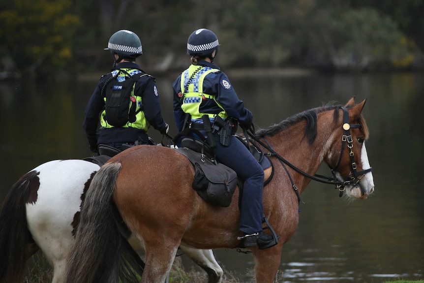 WA Police officers on horseback look out over the Swan River in Maylands.