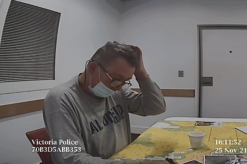 A still from a video shows Greg Lynn sitting at a desk in a police station.