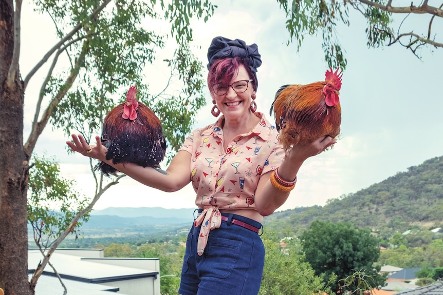 A woman holds up two roosters