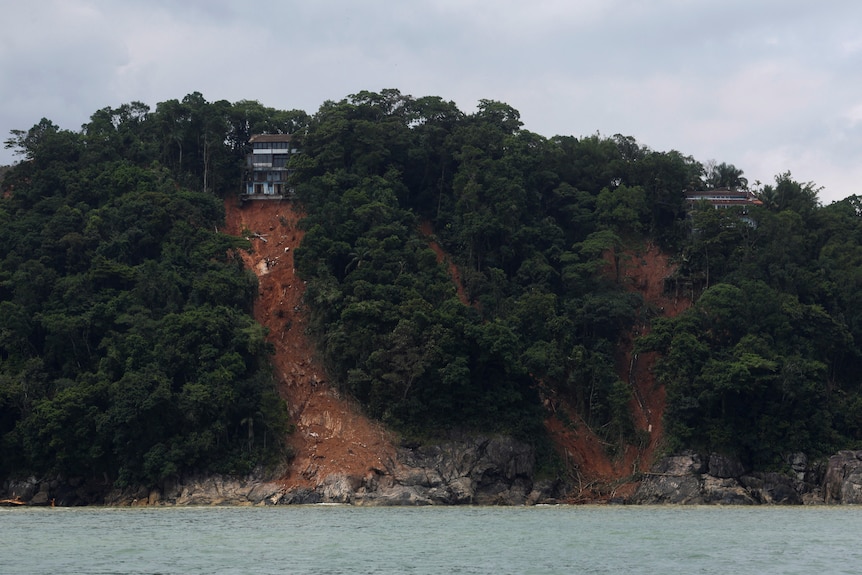 A house on top of a steep slope surrounded in trees and dirt. 