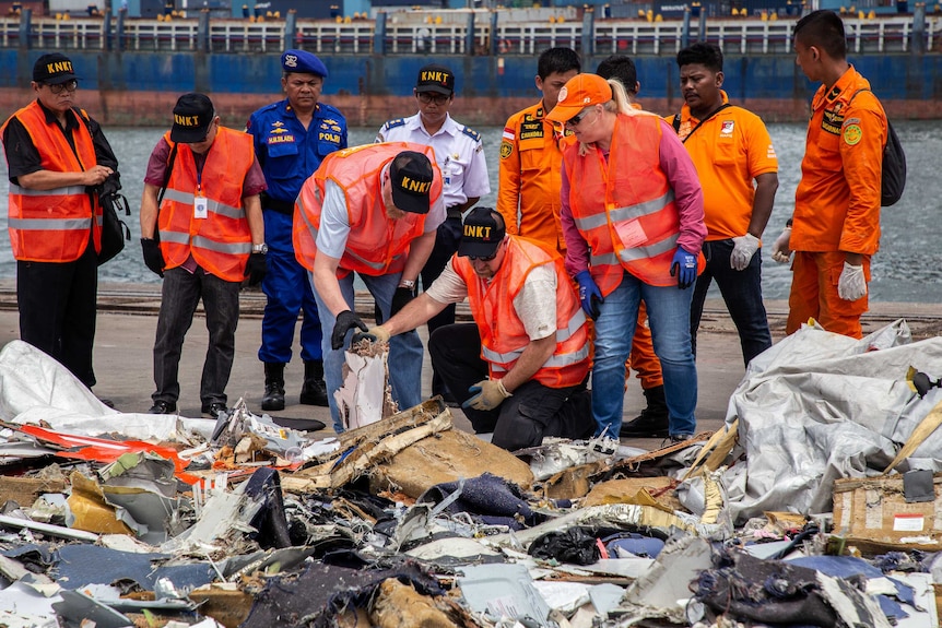 Investigators wearing hi-vis vests inspect wreckage from the Lion Air plane.