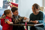 A mother and two children sit at a cafe table.
