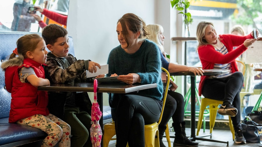 A mother and two children sit at a cafe table.