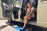 A woman sitting on the step of her van