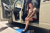 A woman sitting on the step of her van