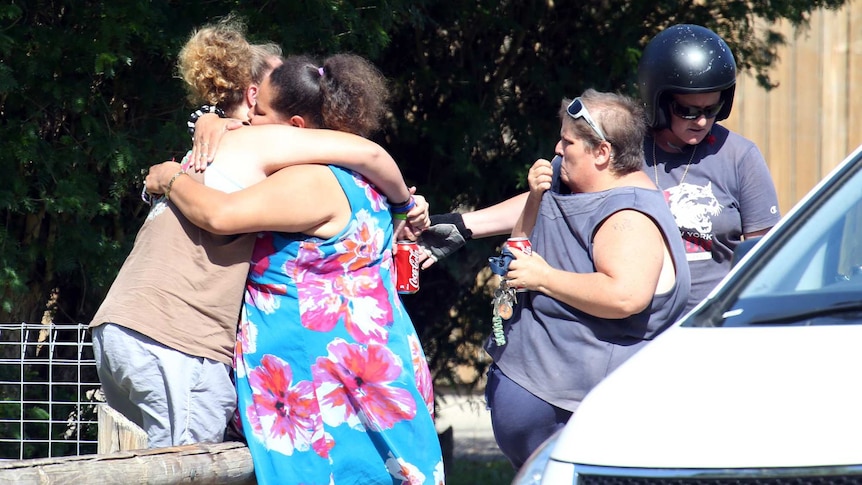 Distraught locals embrace at the scene after eight children were found dead in a house in Manoora near Cairns.