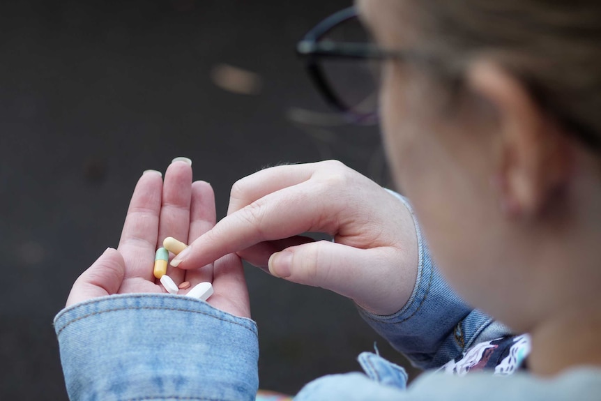 Emily McIntyre holds a handful of pills.