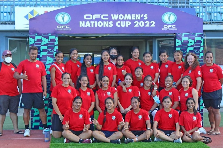 A women's soccer team wearing red and dark blue poses for a photo