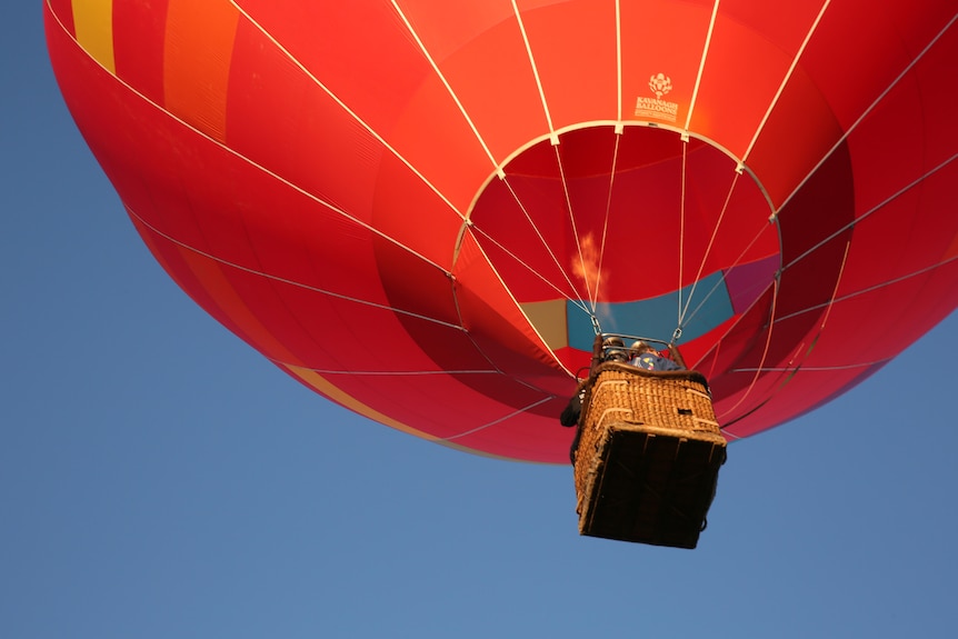 A brightly coloured balloon, as seen from below, against a clear blue sky.