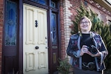 Aged-care consultant and photographer Carolyne Taplin pictured holding her DSLR camera in front of an old doo.