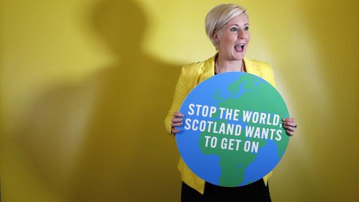 Hannah Bardell poses with a cut-out of the world, with text "stop the world, Scotland wants to get on" written across it.