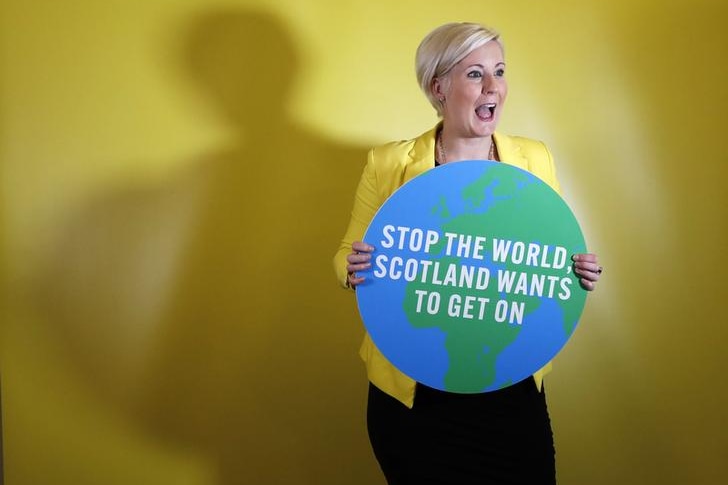 Hannah Bardell poses with a cut-out of the world, with text "stop the world, Scotland wants to get on" written across it.