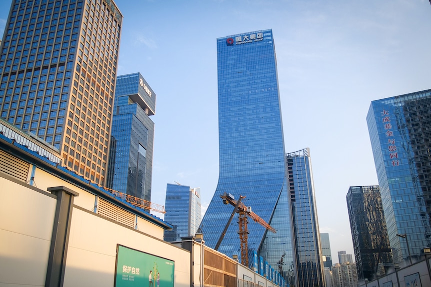 A building soaring into a blue sky, with a crane in front of it 