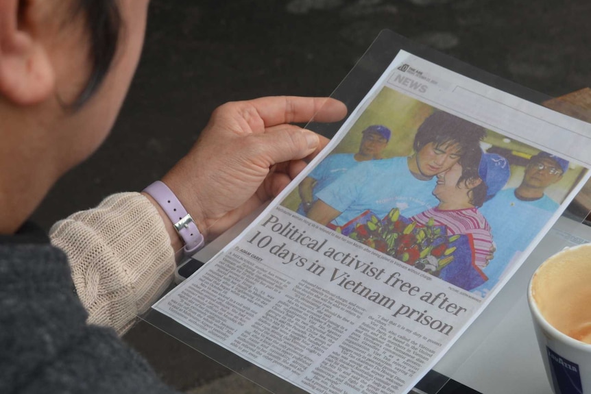 Hong Vo reads a laminated article about her release, picture shows her embracing her youngest son.