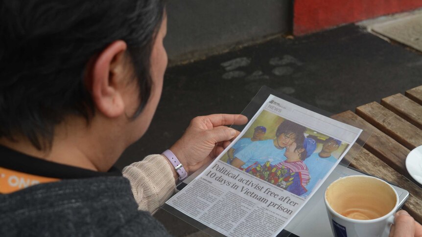 Hong Vo reads a laminated article about her release, picture shows her embracing her youngest son.