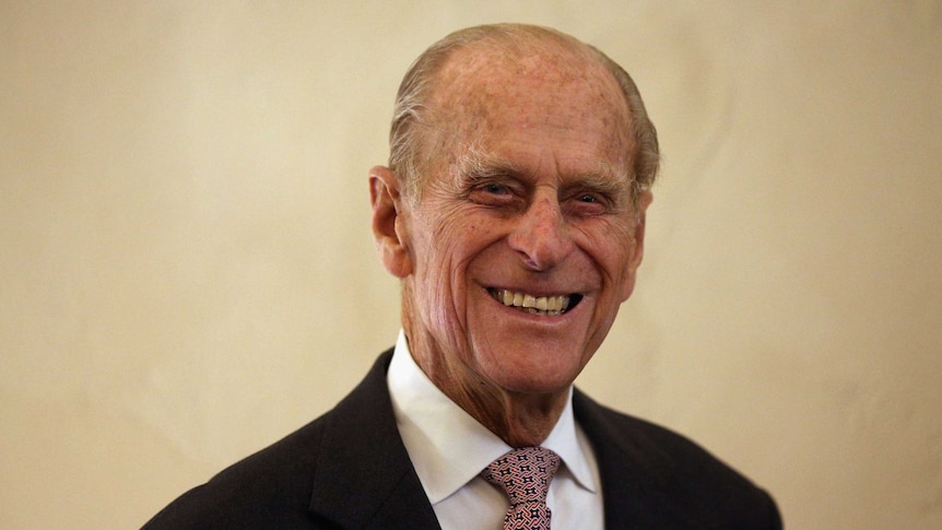 Prince Philip, wearing a suit, smiles in 2012.